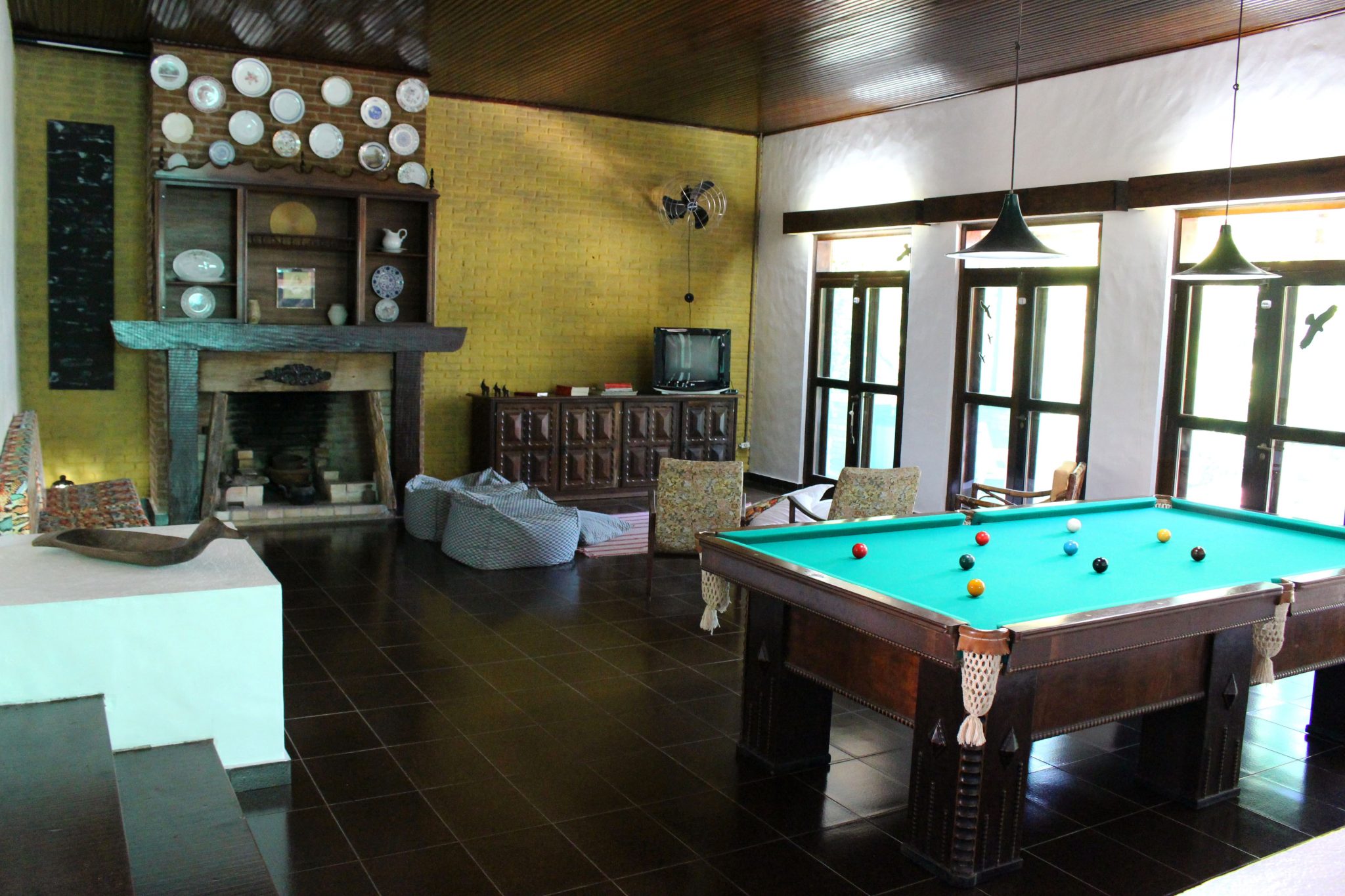 Sala de estar com decoração rústica e mesa de sinuca para lazer (Divulgação/La Viagem)